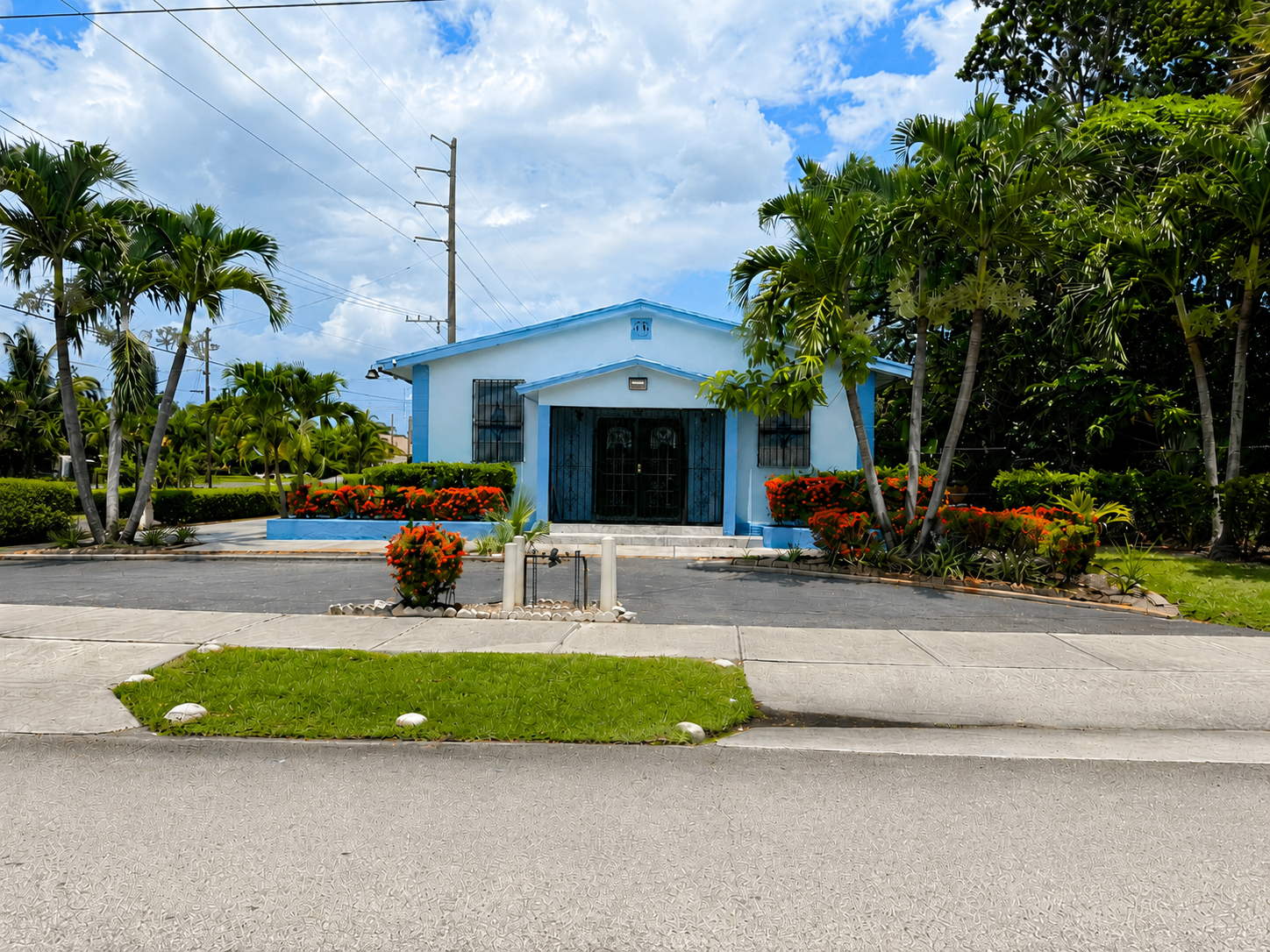 Front view of Cornerstone Full Gospel Assembly church building in Delray Beach — light-blue exterior, arched entrance, tropical landscaping